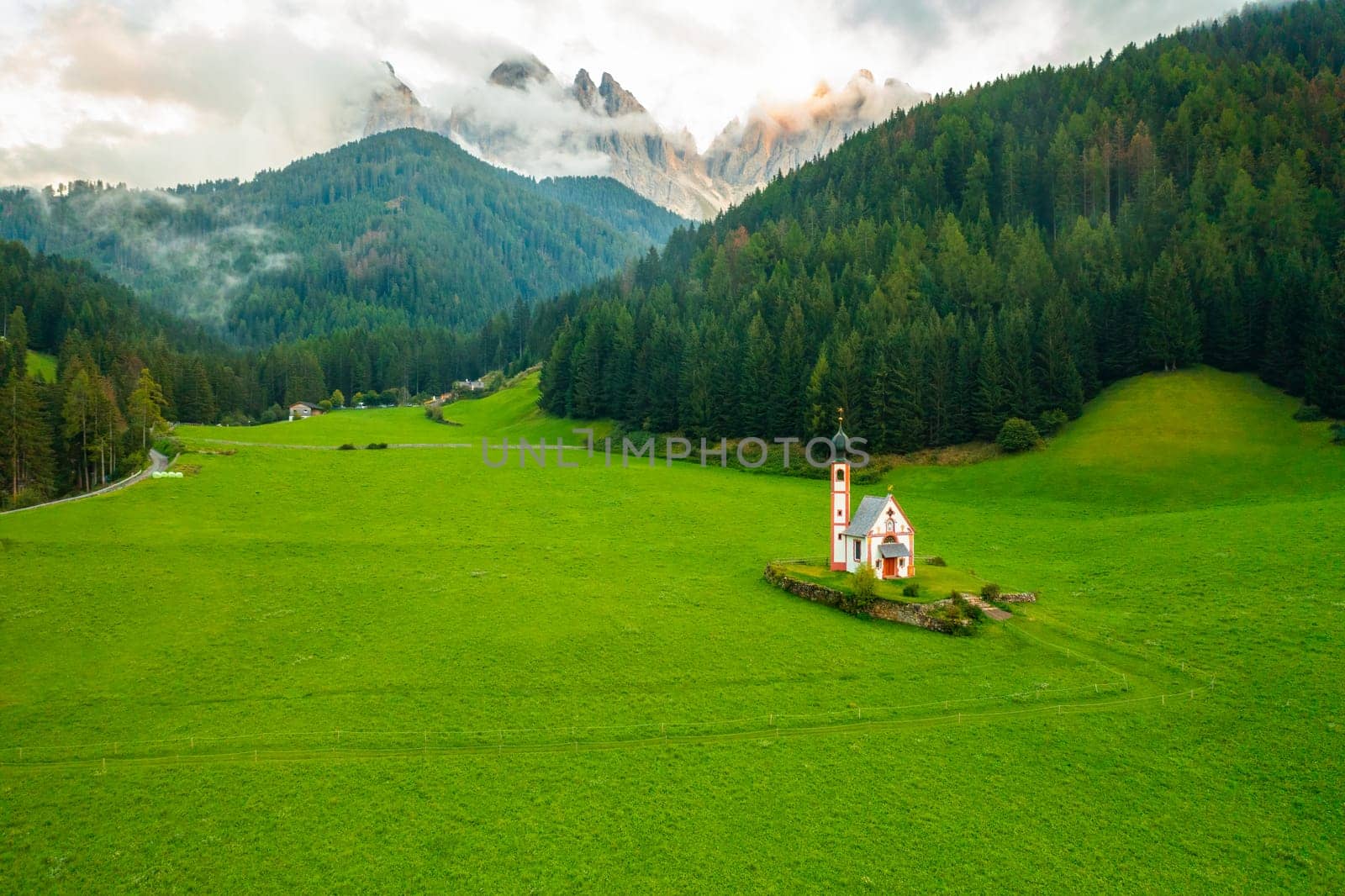 Aerial view of the Church of St. Johann against the Geisler peaks in Santa Maddalena village by vladimka