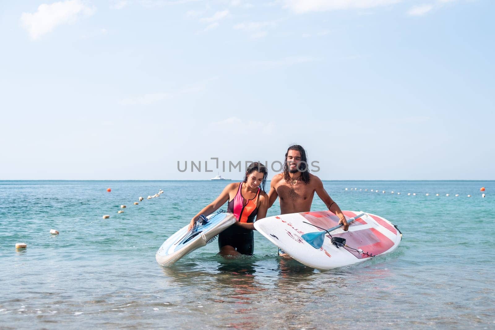 Woman man sea sup. Close up portrait of beautiful young caucasian woman with black hair and freckles looking at camera and smiling. Cute woman portrait in a pink bikini posing on sup board in the sea by panophotograph