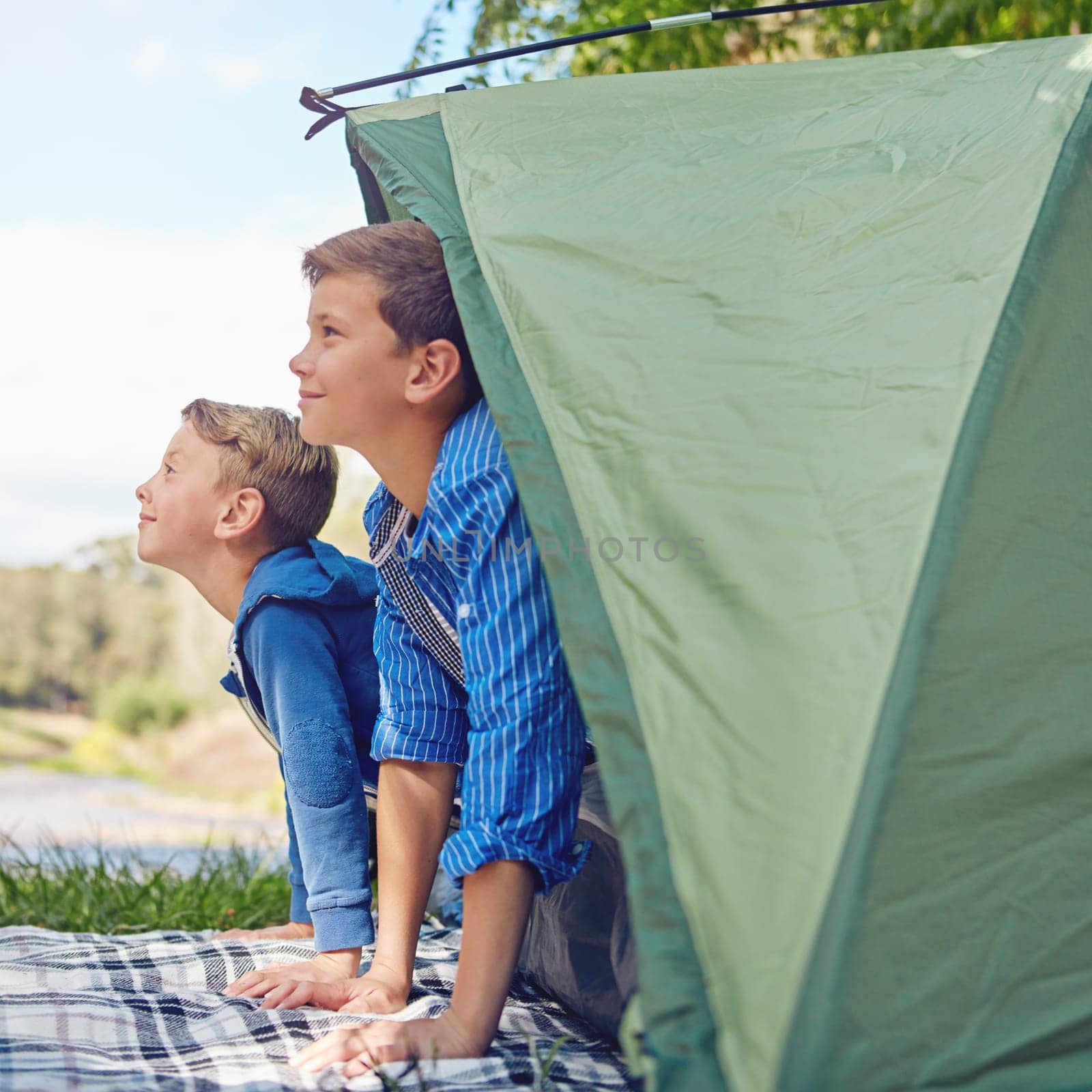 They love camping. two young brothers exiting in their tent. by YuriArcurs