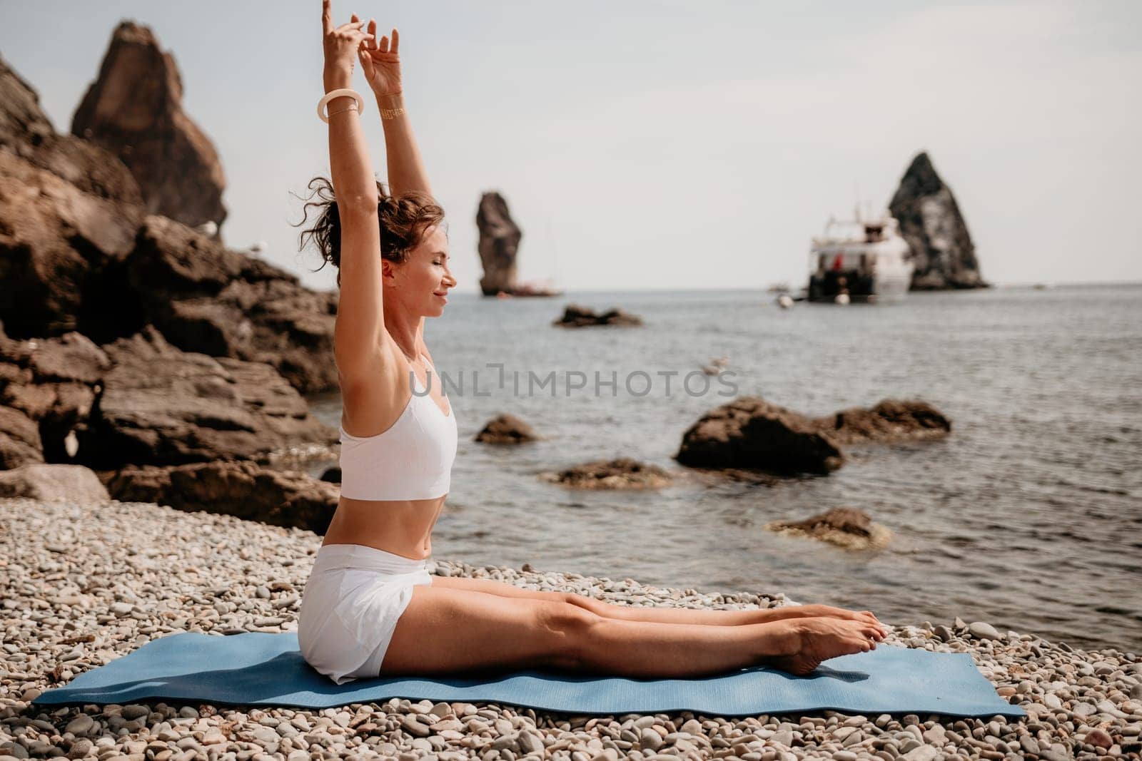 Woman sea yoga. Two Happy women meditating in yoga pose on the beach, ocean and rock mountains. Motivation and inspirational fit and exercising. Healthy lifestyle outdoors in nature, fitness concept. by panophotograph