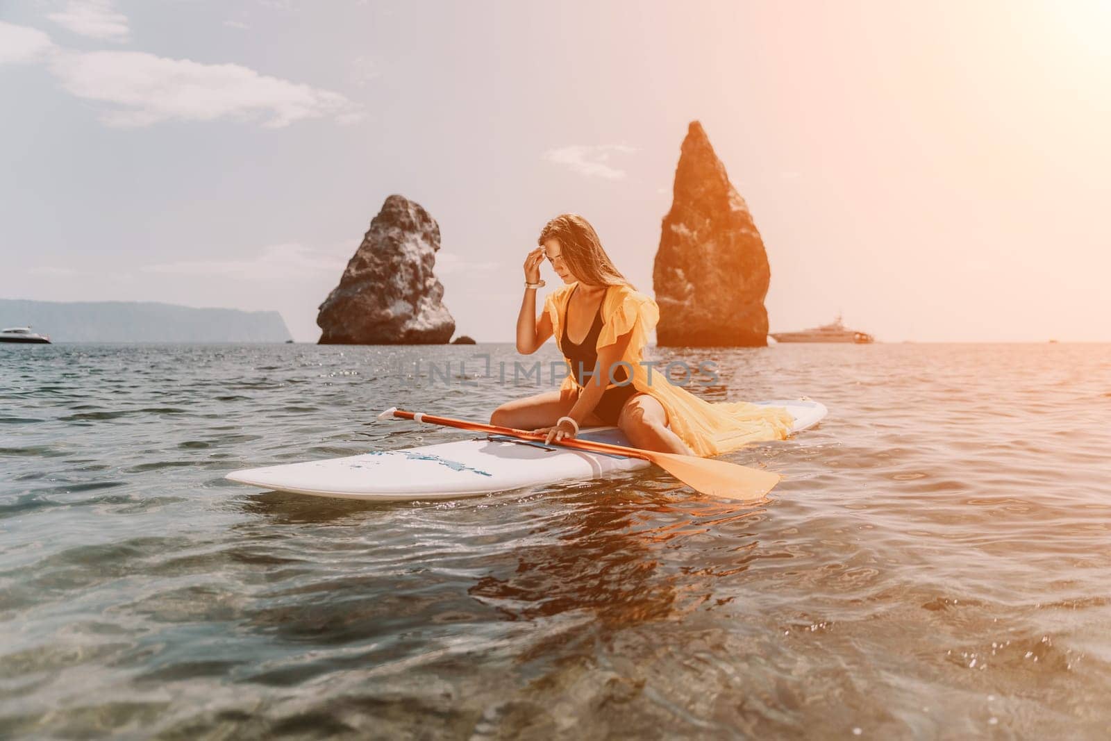 Woman sea sup. Close up portrait of happy young caucasian woman with long hair looking at camera and smiling. Cute woman portrait in bikini posing on sup board in the sea by panophotograph