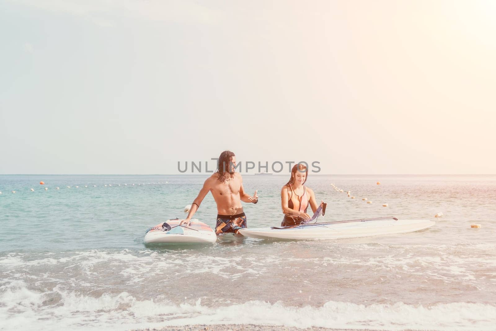 Woman man sea sup. Close up portrait of beautiful young caucasian woman with black hair and freckles looking at camera and smiling. Cute woman portrait in a pink bikini posing on sup board in the sea by panophotograph