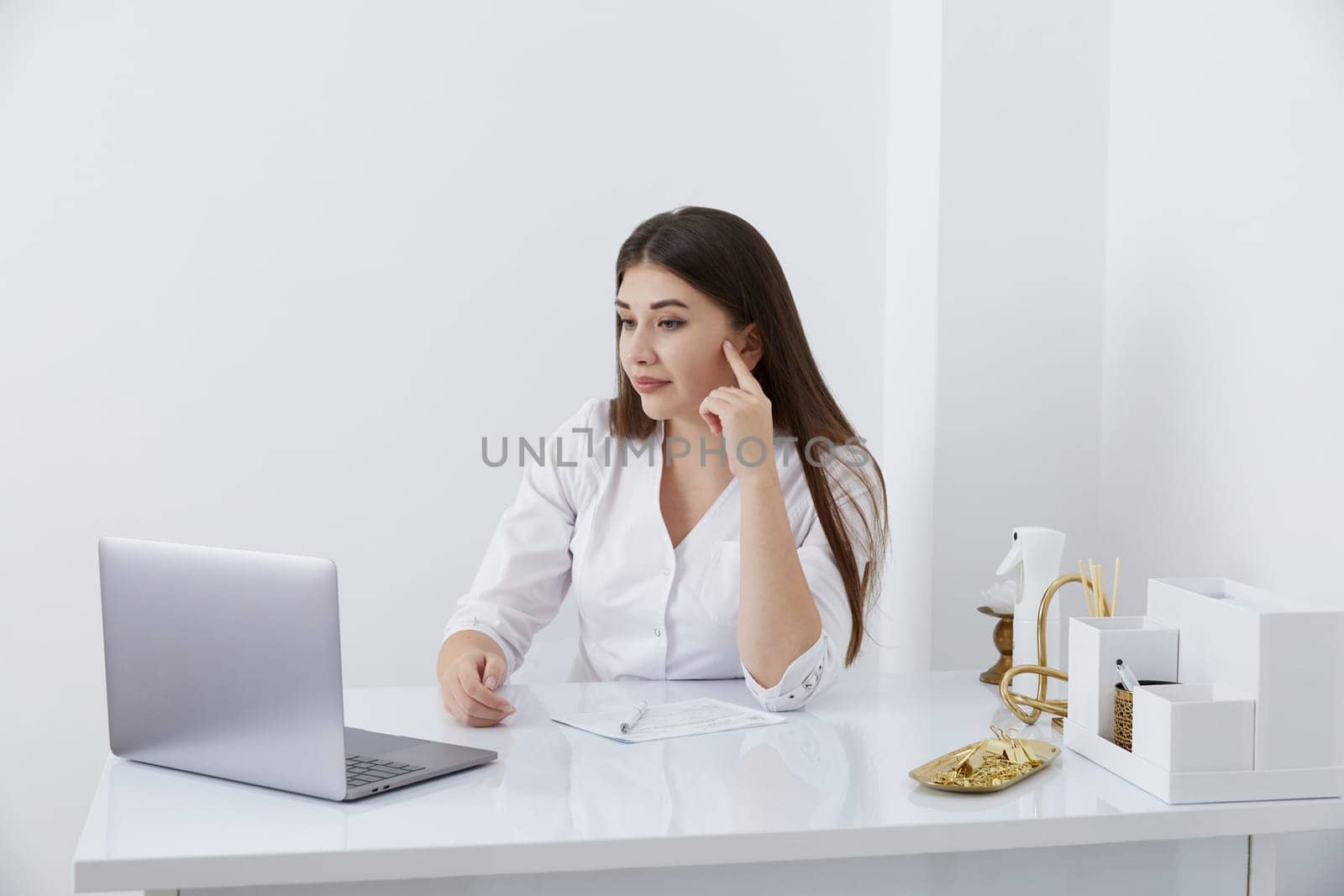Portrait of female doctor talking to online patient on laptop screen sitting at clinic office desk giving online consultation for domestic health treatment by Mariakray