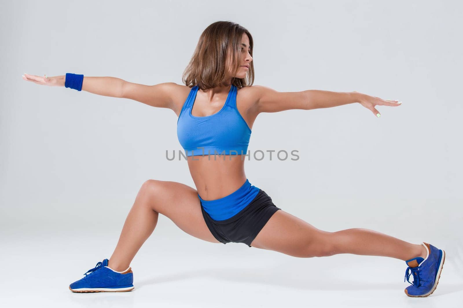 Sport and active lifestyle. Sporty flexible girl fitness woman in blue sportswear doing stretching exercise on light background.