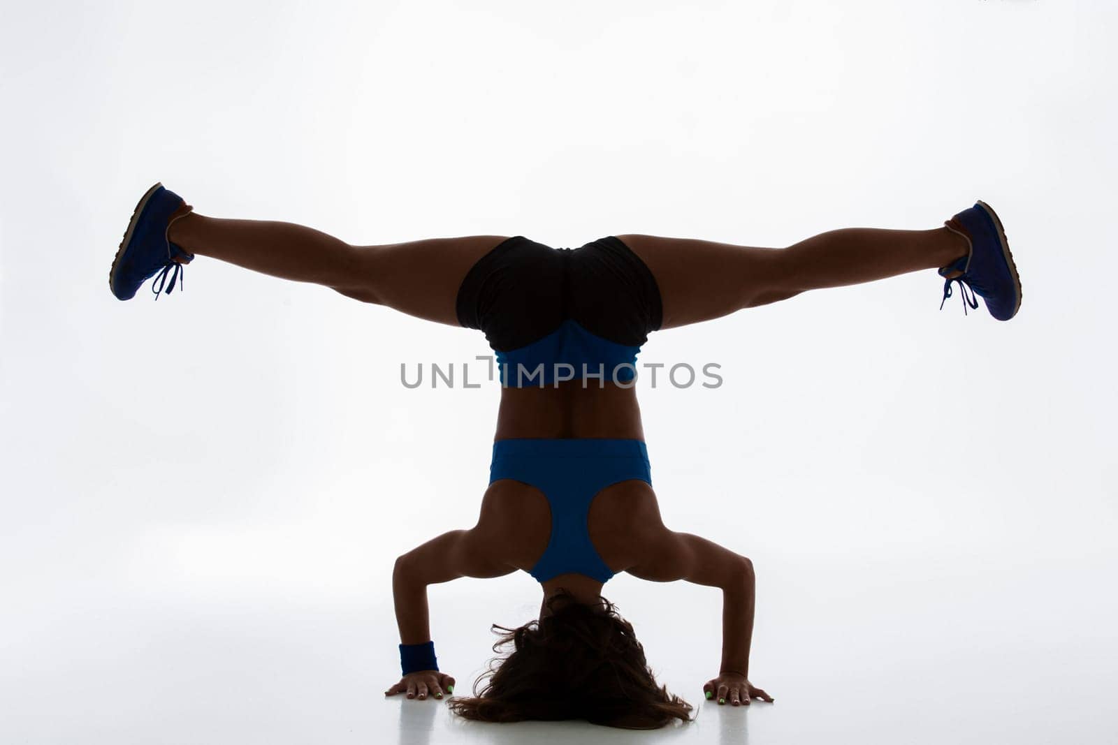 Sport and active lifestyle. Sporty flexible girl fitness woman in sportswear doing stretching exercise on light background. silhouette