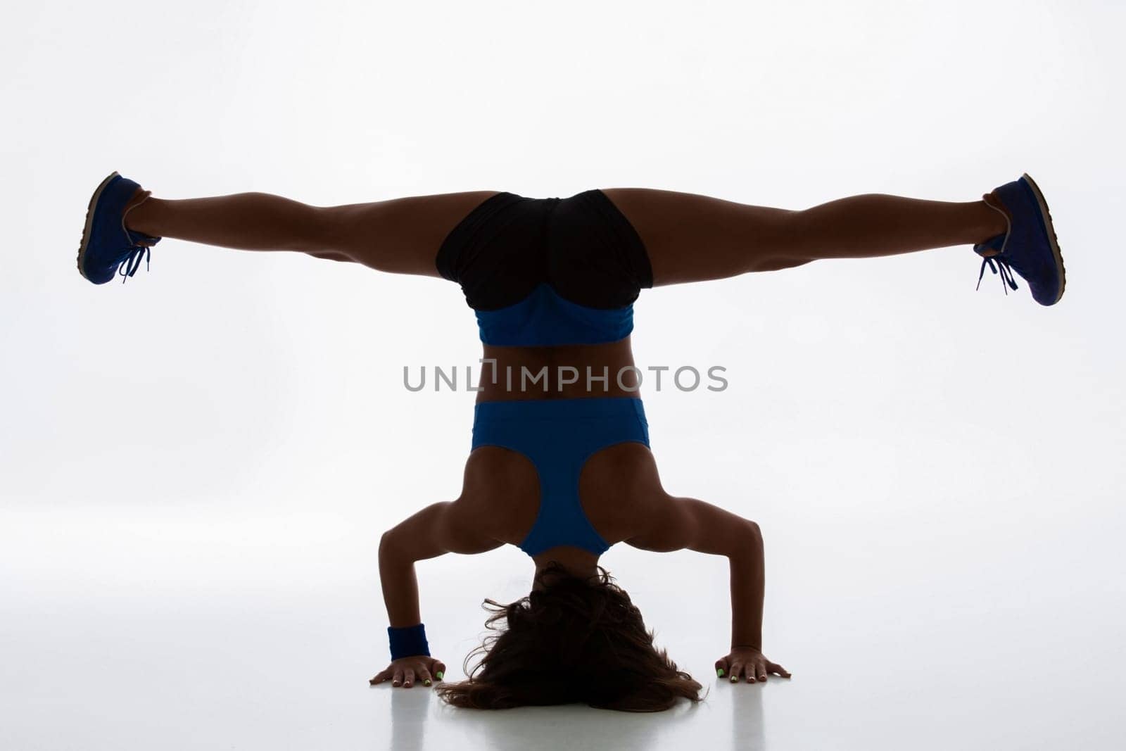 Sport and active lifestyle. Sporty flexible girl fitness woman in sportswear doing stretching exercise on light background. silhouette