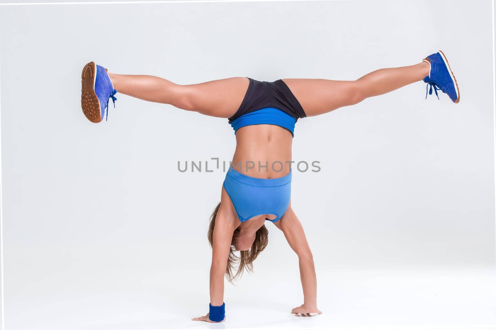 Sport and active lifestyle. Sporty flexible girl fitness woman in blue sportswear doing stretching exercise on light background.