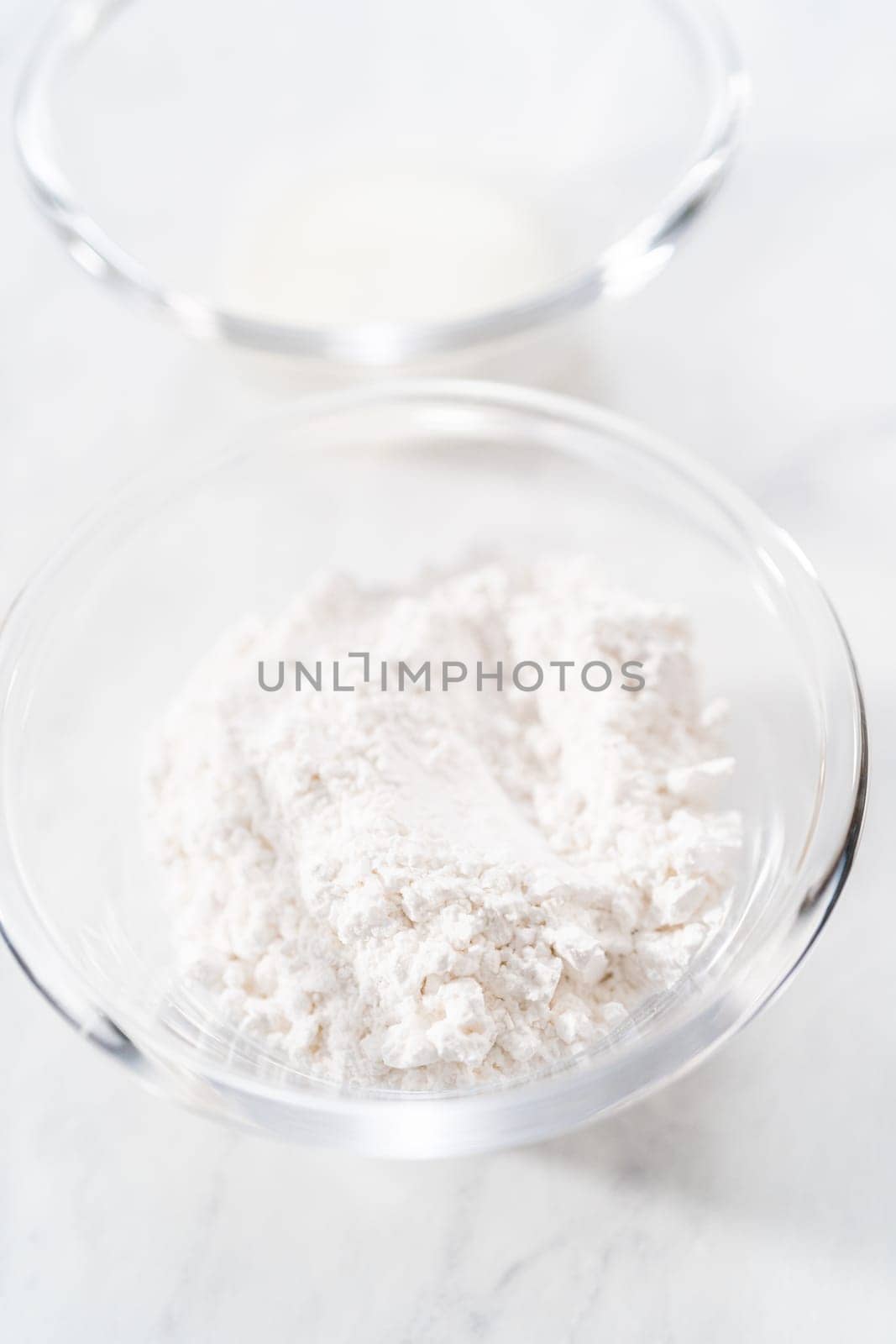 Measured ingredients in glass bowls to prepare a white bread glaze.