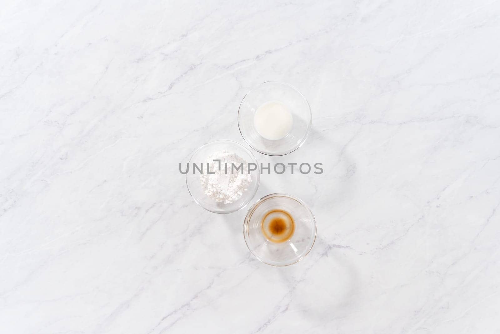 Flat lay. Measured ingredients in glass bowls to prepare a white bread glaze.