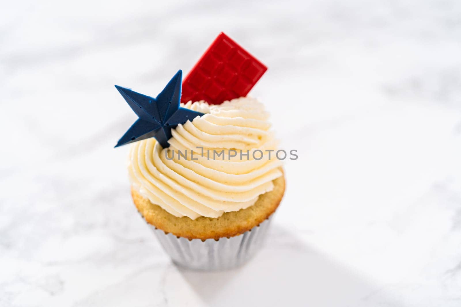 Lemon cupcakes with lemon buttercream frosting, and decorated with patriotic blue chocolate star and red mini chocolate.