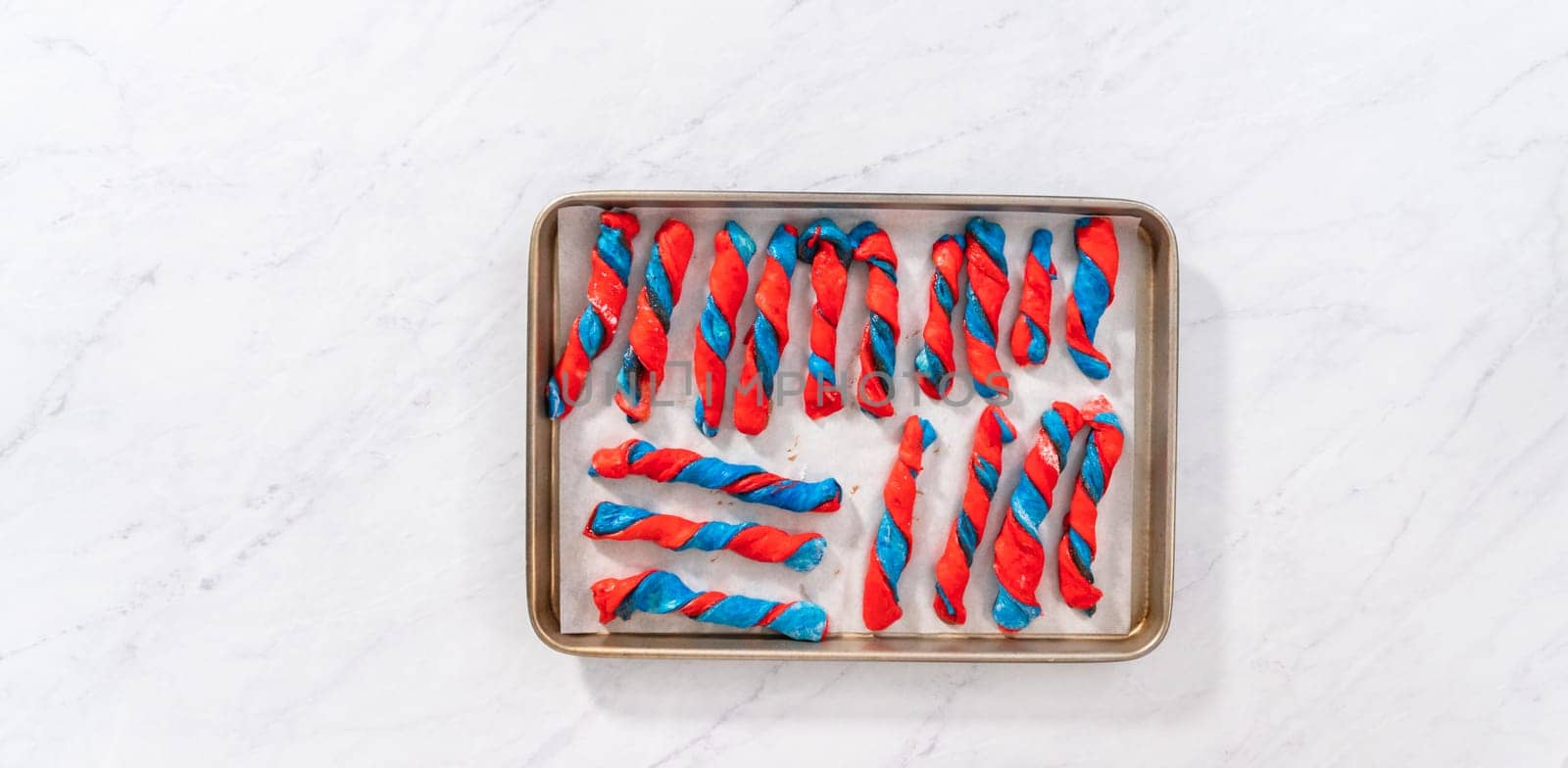 Flat lay. Rising patriotic cinnamon twists on the baking sheet lined with parchment paper.