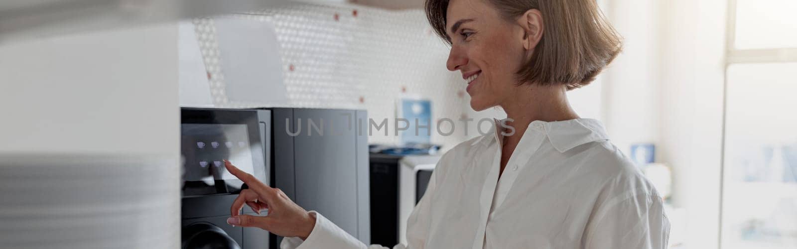 Smiling business woman in casual clothes making a coffee in office kitchen during break by Yaroslav_astakhov