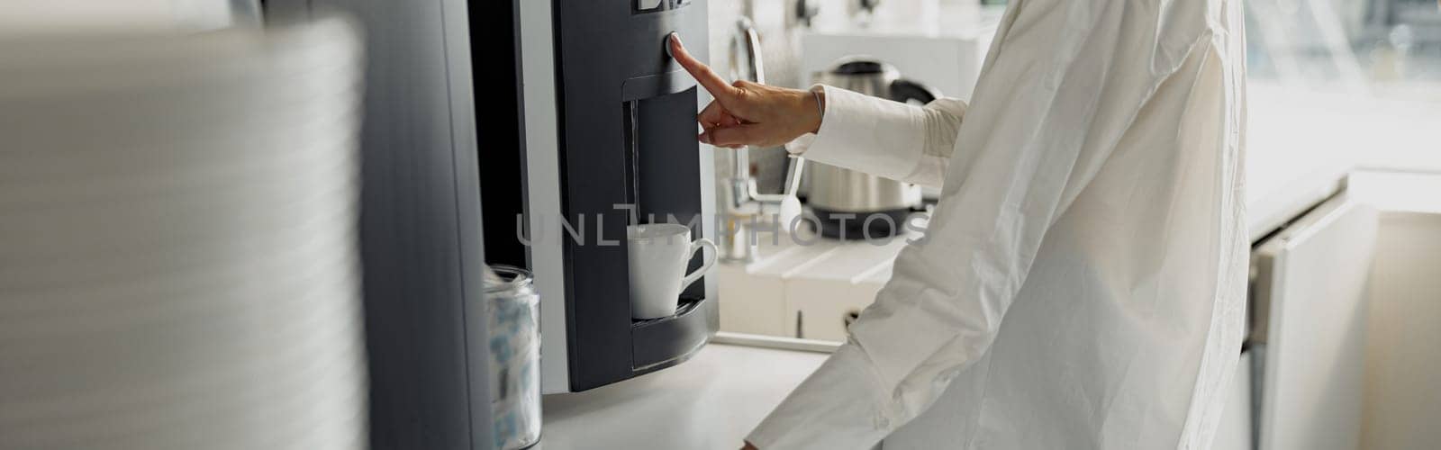 Business woman in casual clothes making a coffee in office kitchen during break. High quality photo