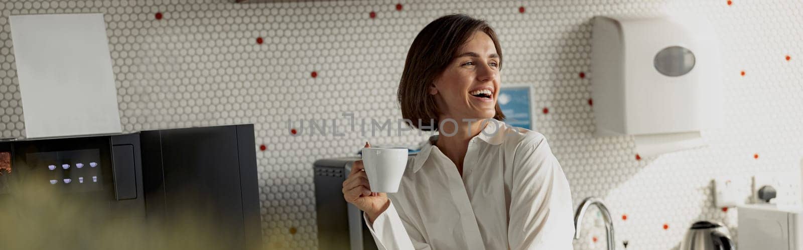 Business woman in casual clothes drinking coffee in office kitchen during break. High quality photo