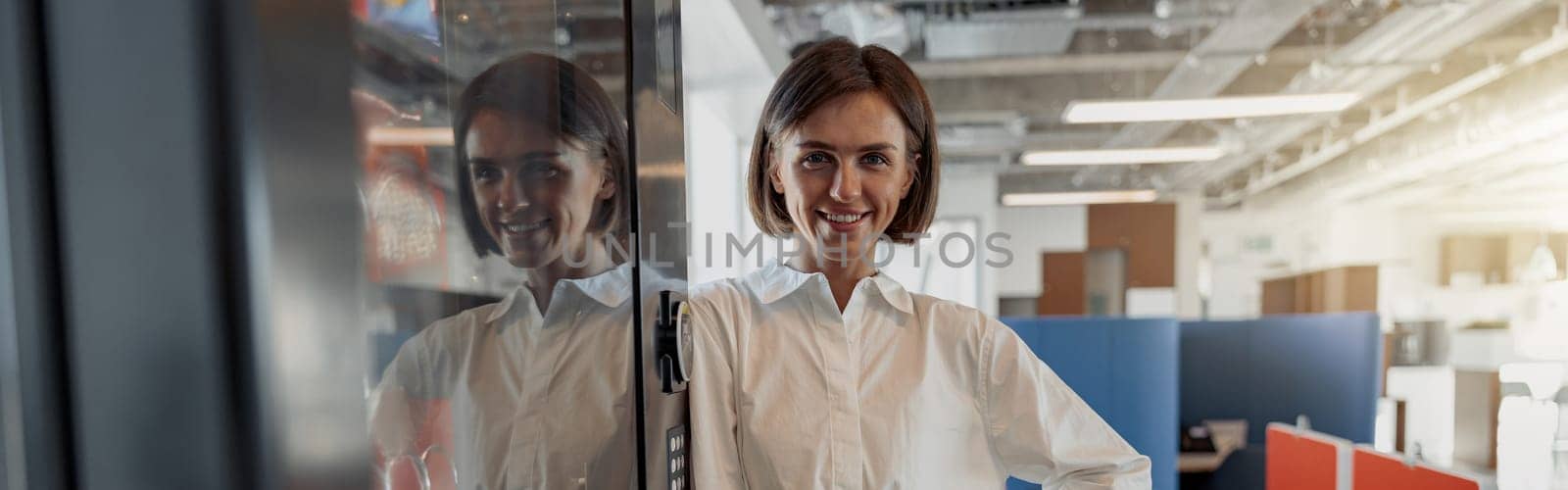Portrait of attractive european business woman standing in modern office and looking at camera