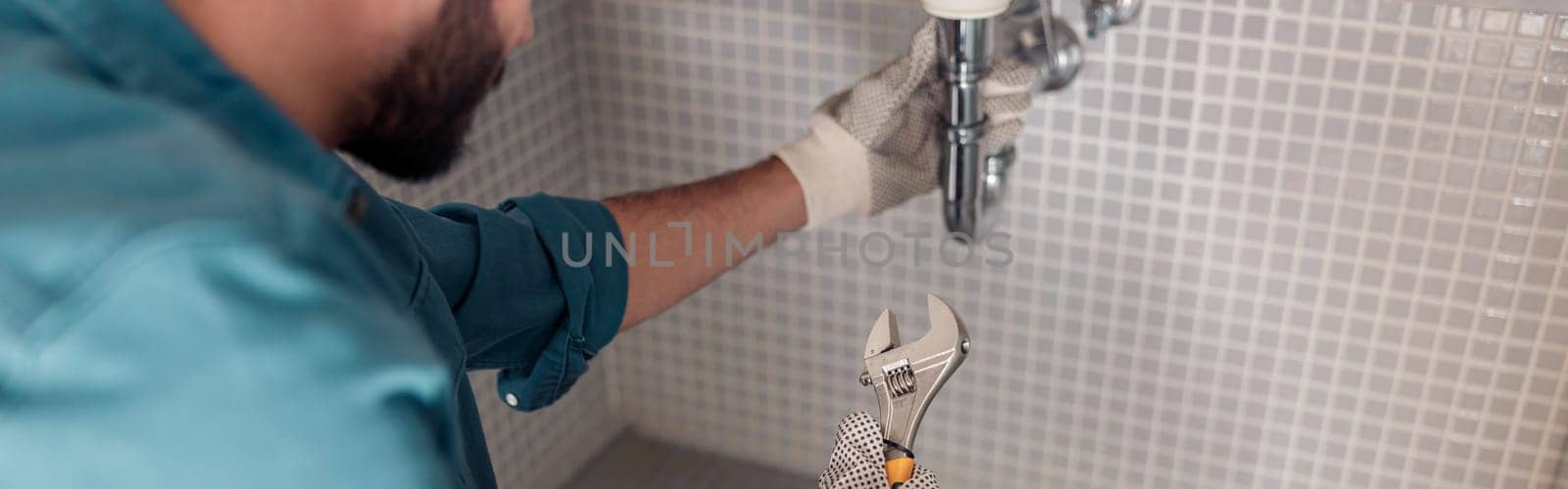 Close up of plumber is repairing faucet of a sink at bathroom using adjustable wrench by Yaroslav_astakhov