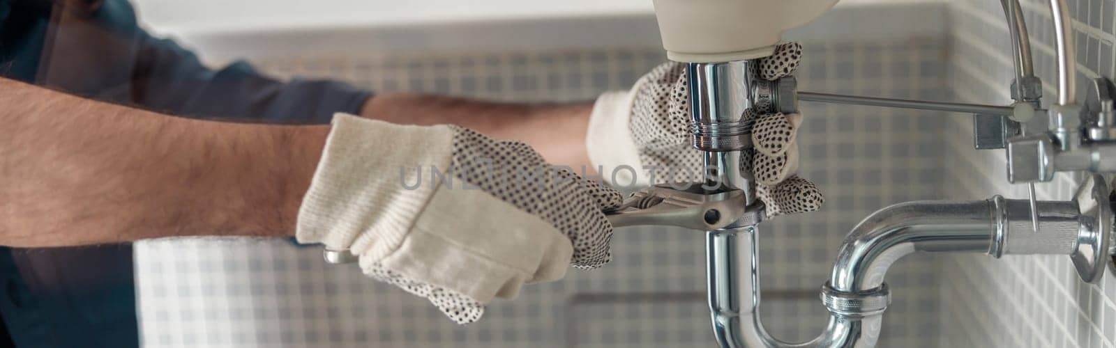 Close up of indian plumber is repairing faucet of a sink at bathroom using adjustable wrench by Yaroslav_astakhov