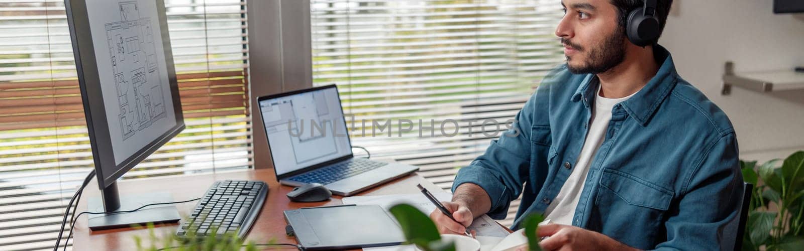 Focused man interior designer in headphones works in home office. High quality photo