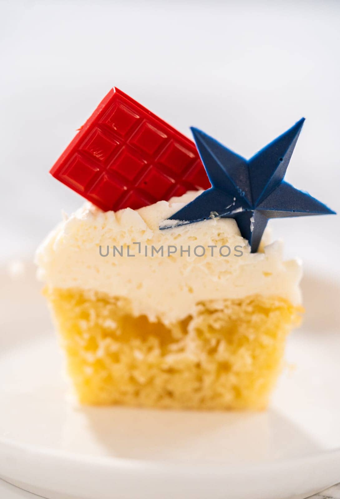 Sliced lemon cupcakes with lemon buttercream frosting, and decorated with patriotic blue chocolate star and red mini chocolate.