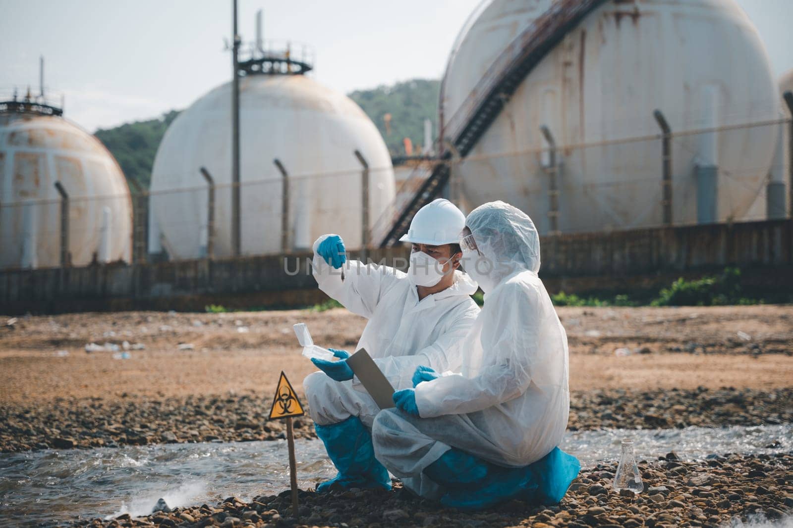 Biologist wear protective suit and mask collects sample of waste water from industry by Sorapop