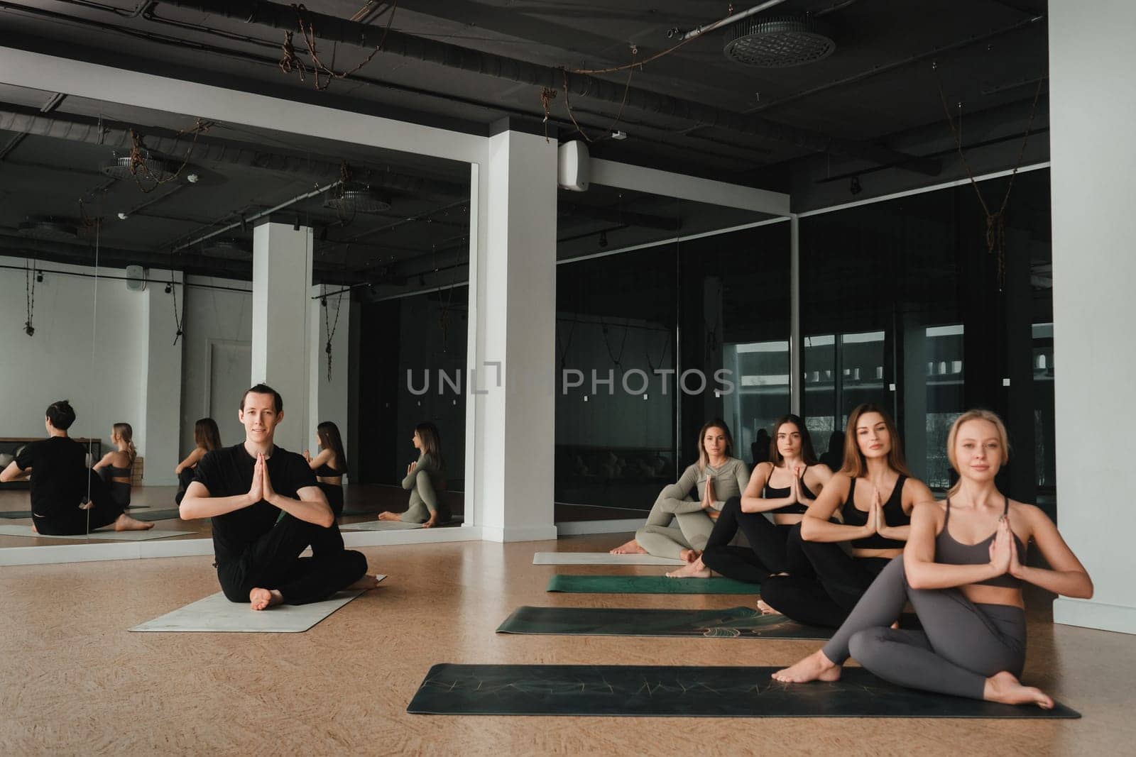 a group of girls do yoga in the gym under the guidance of a coach.