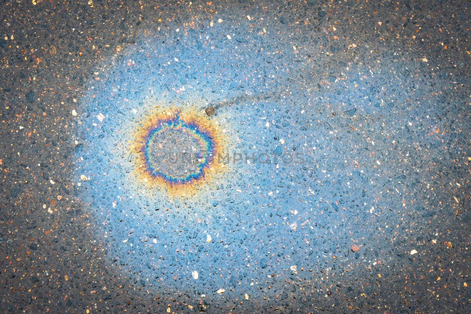 Fuel stain on wet asphalt. Colored stains from a gasoline leak on the road.