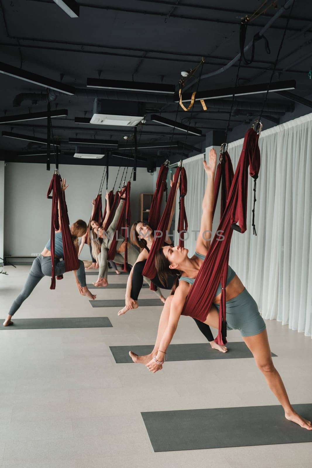 A group of women play sports on hanging hammocks. Fly yoga in the gym.