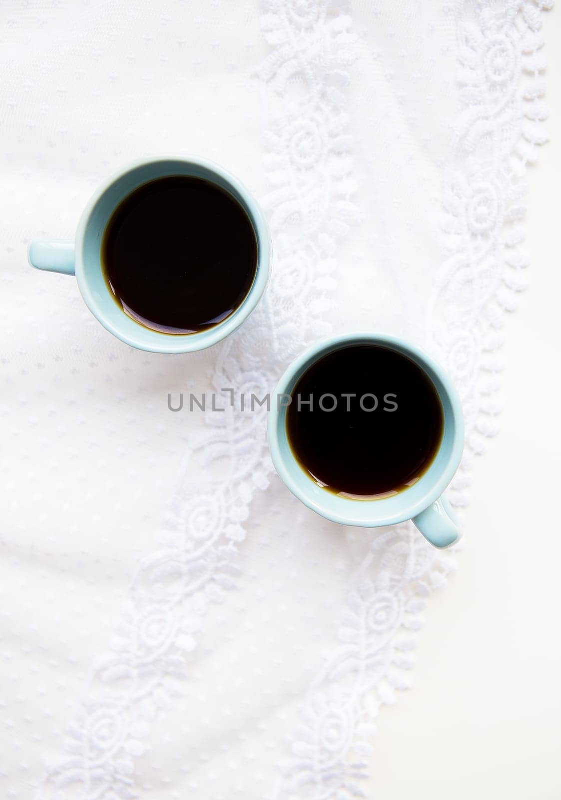 two cups of coffee with croissants on the background of laces on a white background, close-up