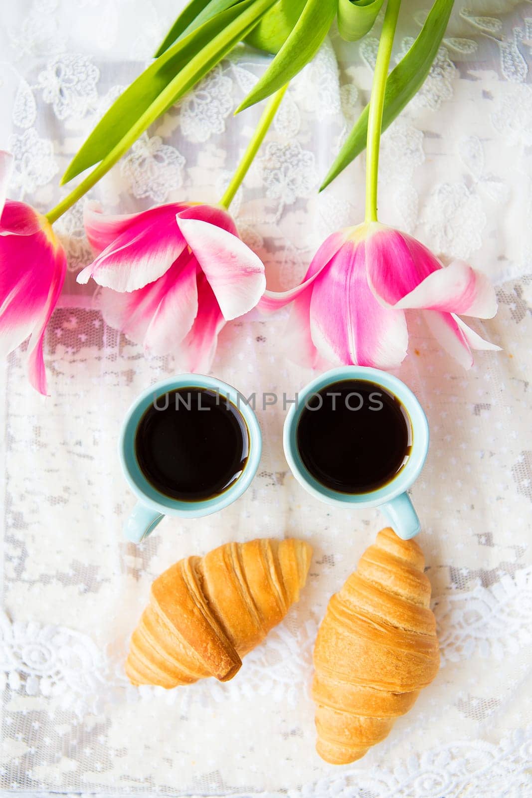 nice cup of coffee, croissants and pink tulips on old white table, close-up by sfinks