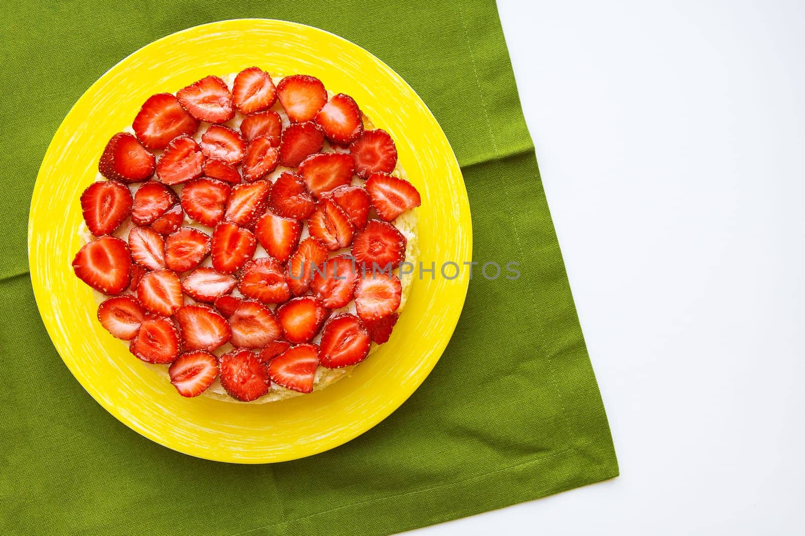 Beautiful strawberry cake is on the table, green napkin.