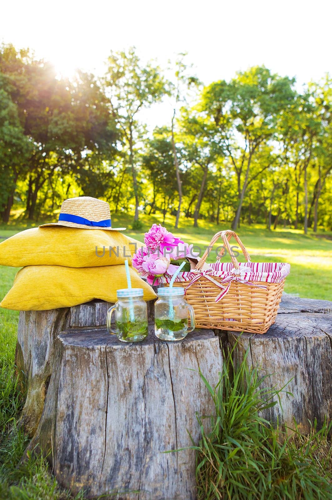 Beautiful basket stands on a wooden stump with flowers and drinks