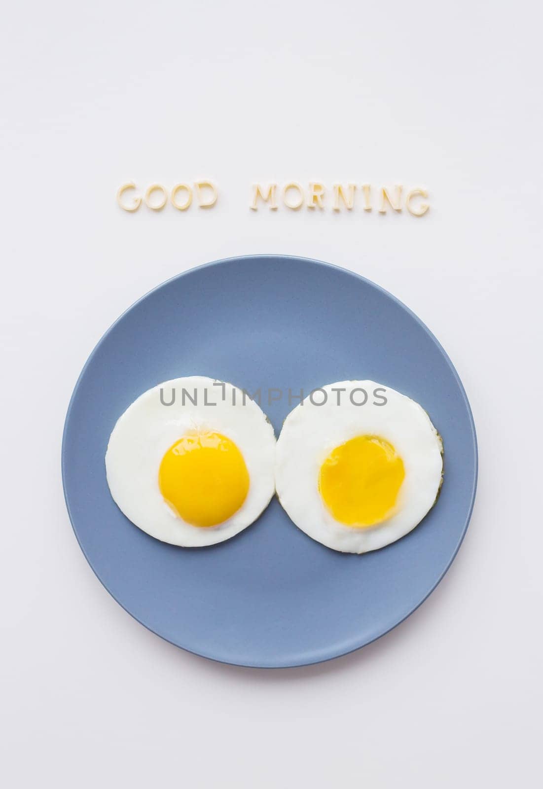 two eggs on a plate and a yellow napkin, inscription Good Morning