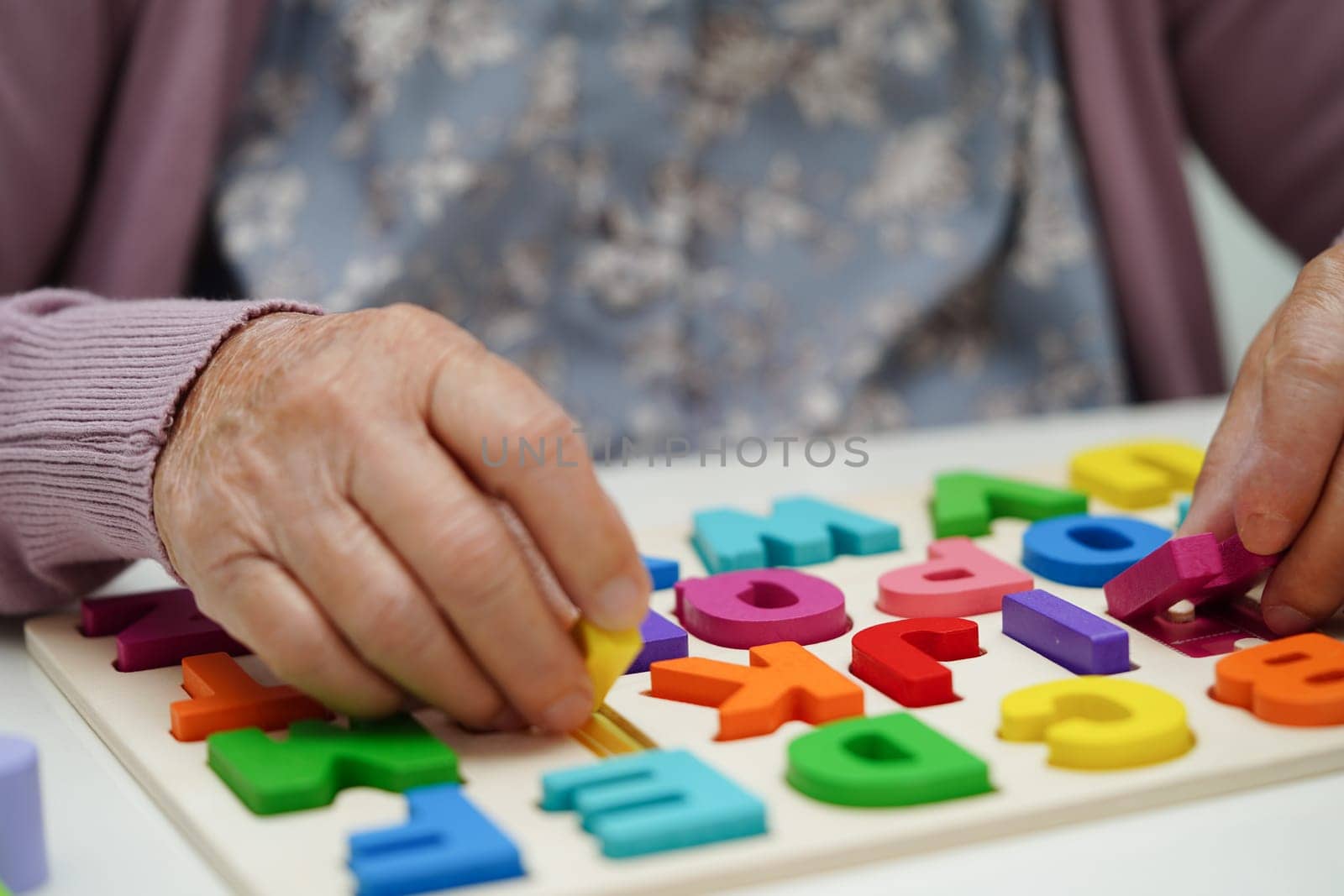 Asian elderly woman playing puzzles game to practice brain training for dementia prevention, Alzheimer disease.