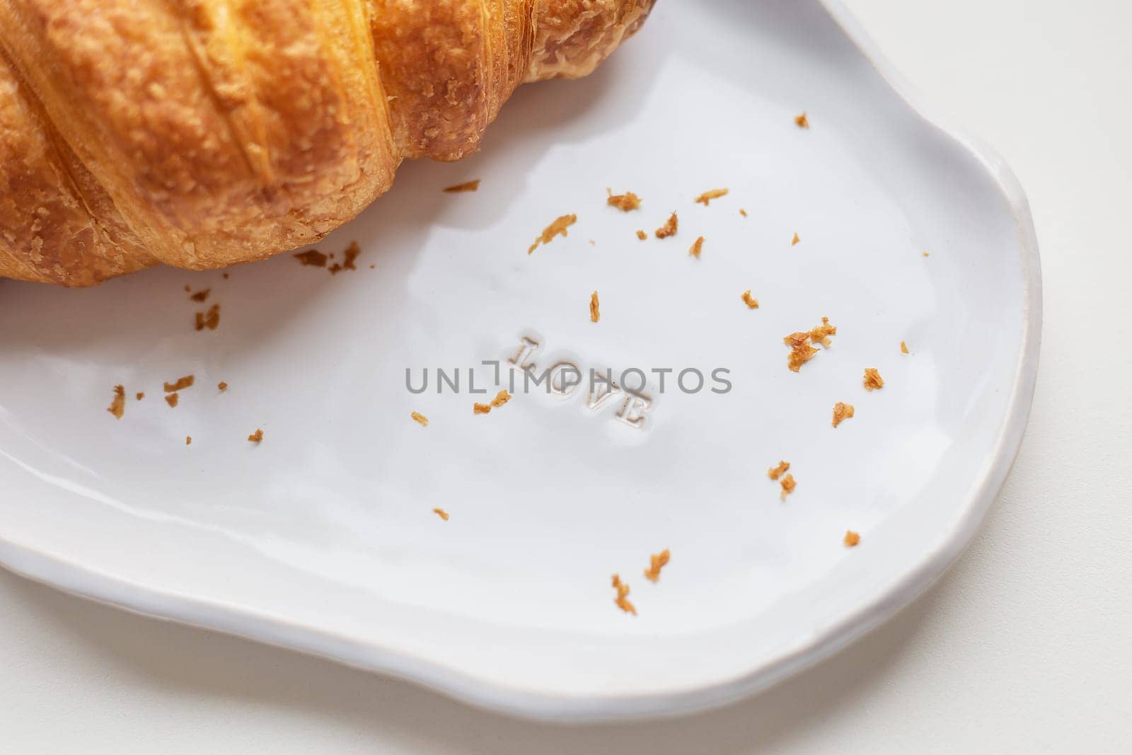 White handmade clay plate with fresh croissant on a white table