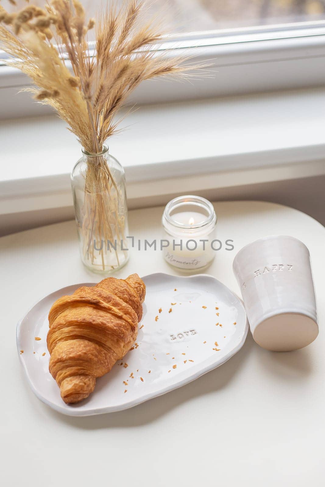 White glass and a plate on which there is a croissant made of clay with an inscription, handmade. by sfinks