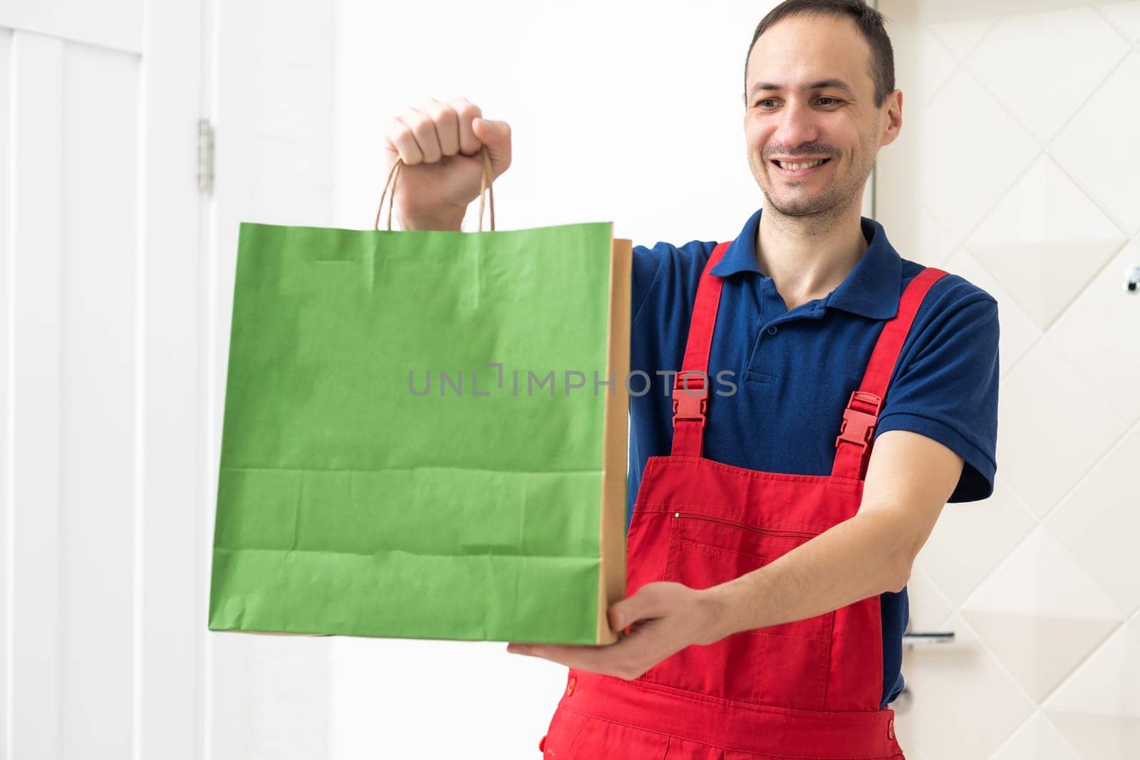 Side view of delivery man with box in studio. isolated gray background. High quality photo