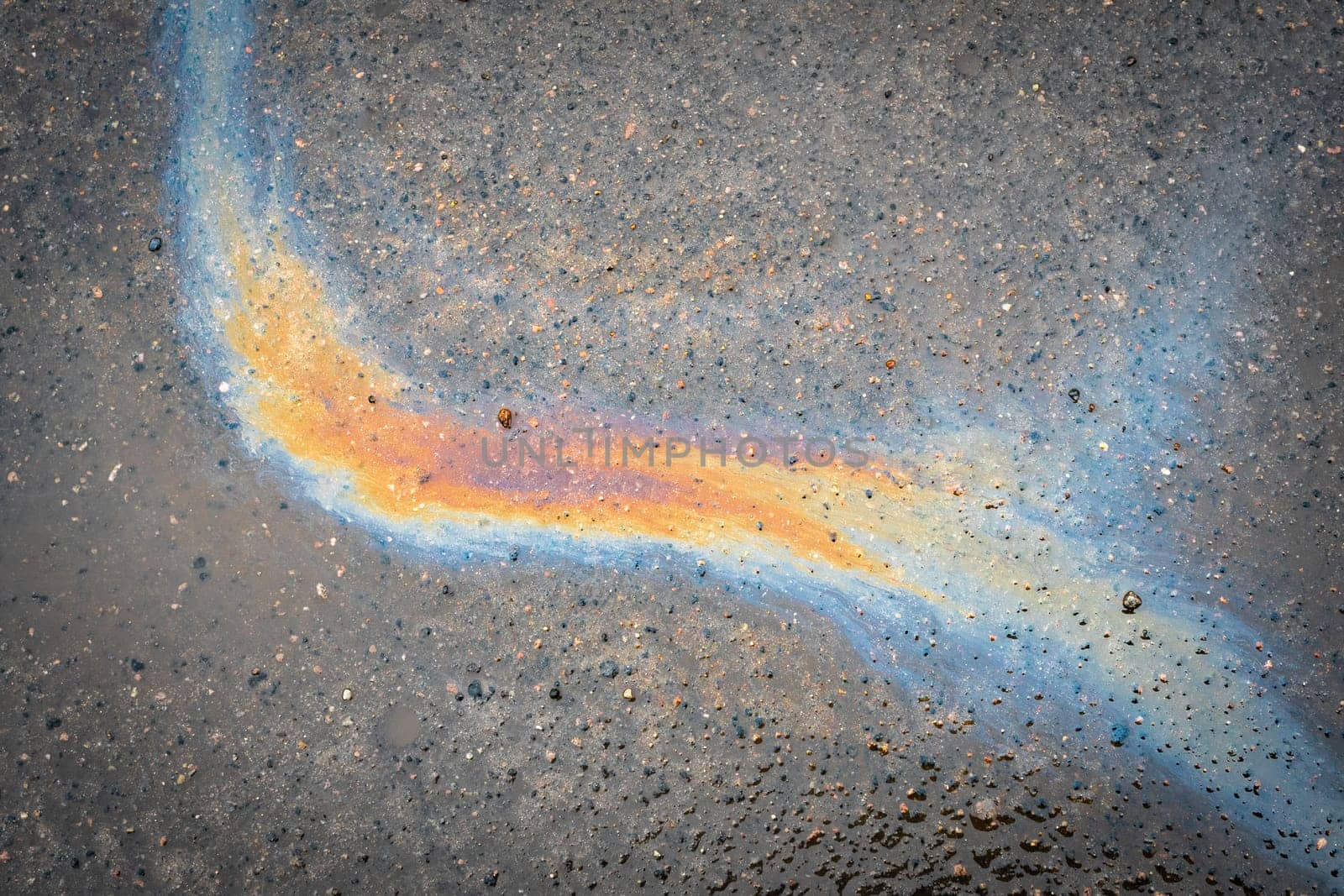 Rainbow gasoline oil spill on the pavement as a texture or background.