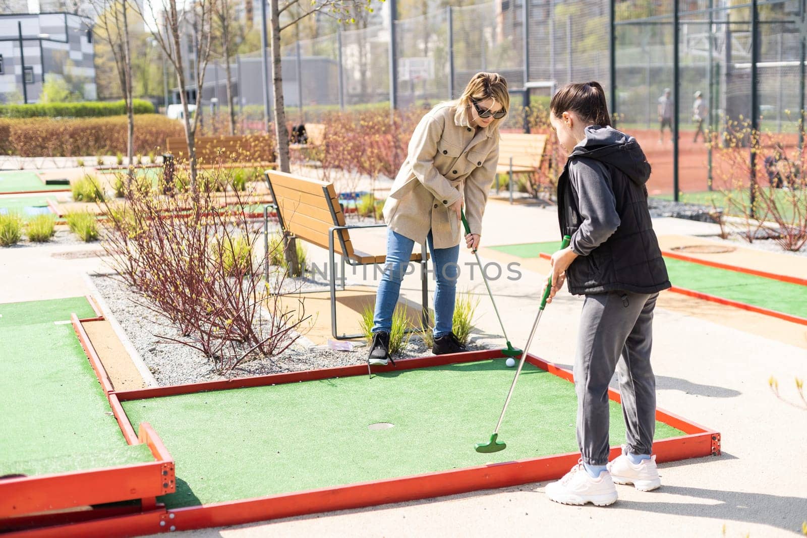 mother and daughter enjoying together playing mini golf in the city