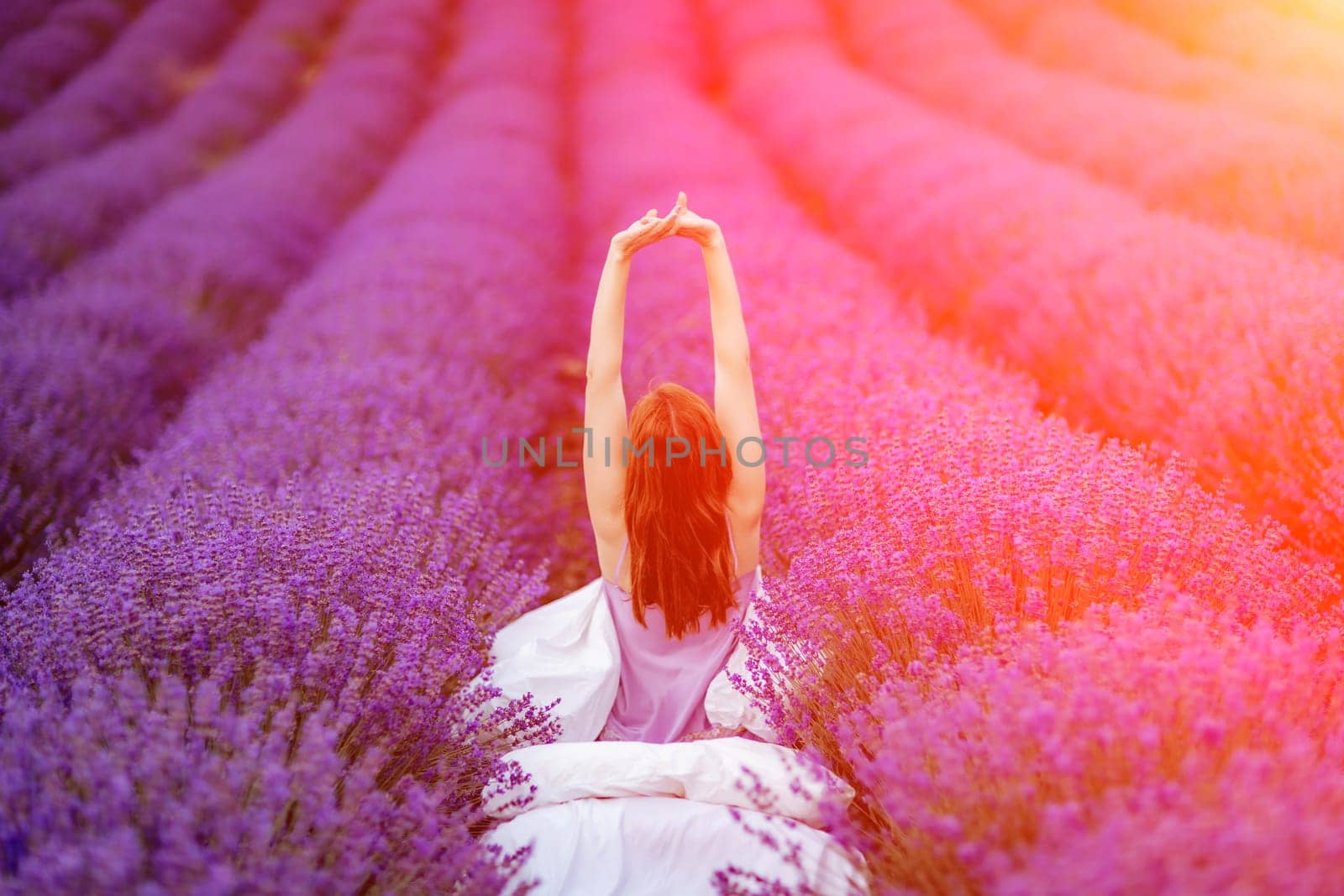 A middle-aged woman sits in a lavender field and enjoys aromatherapy. Aromatherapy concept, lavender oil, photo session in lavender.