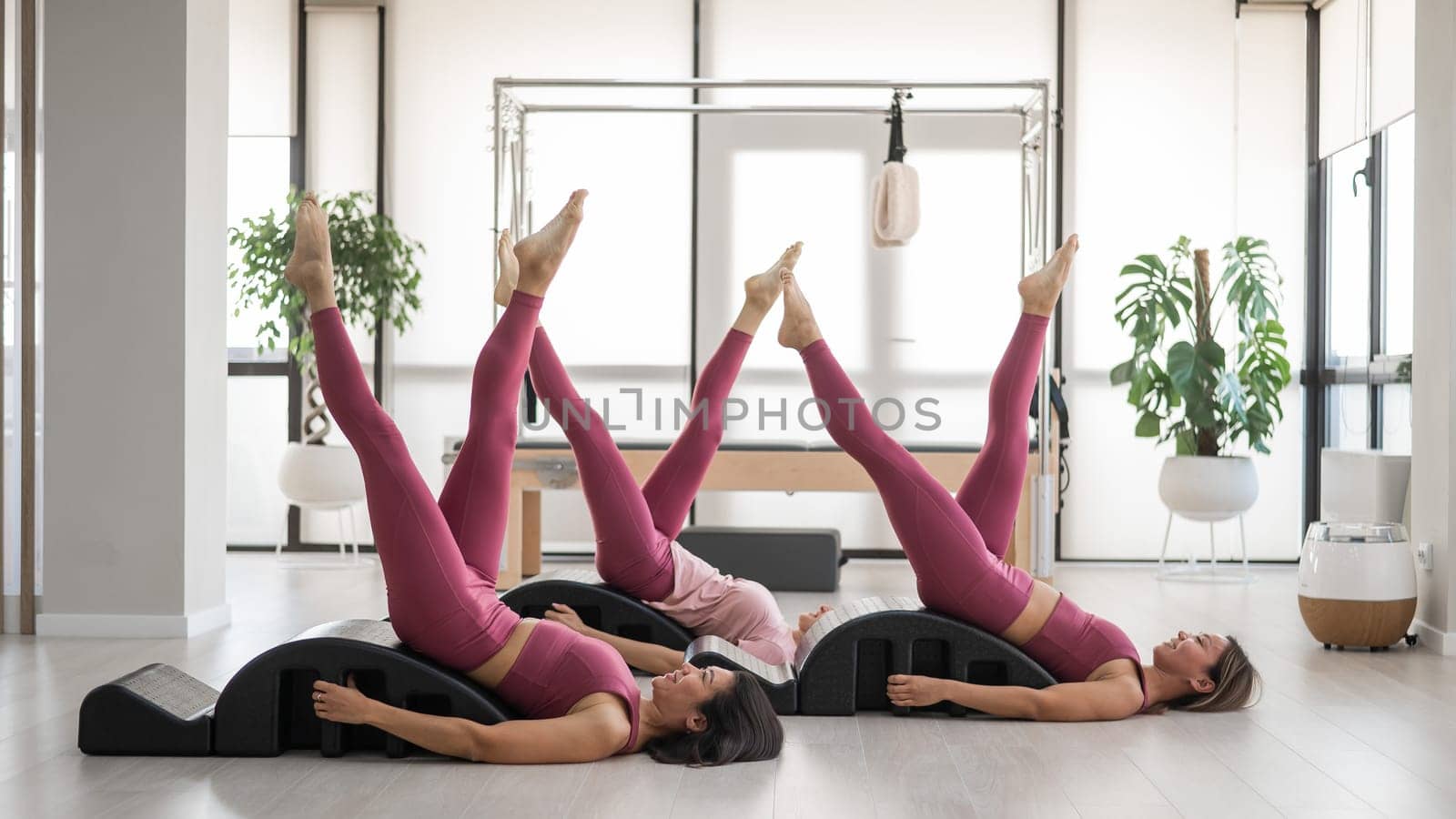 Balanced Body Pilates Arc. Three asian women exercising on pilates arc