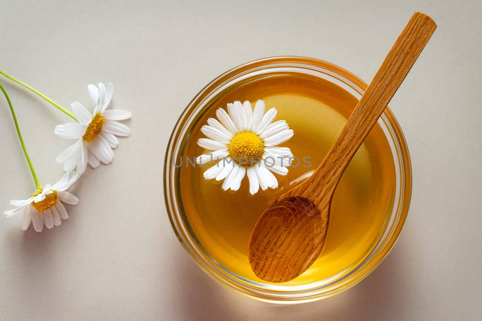 Chamomile syrup in a small bowl and jar on the kitchen table.