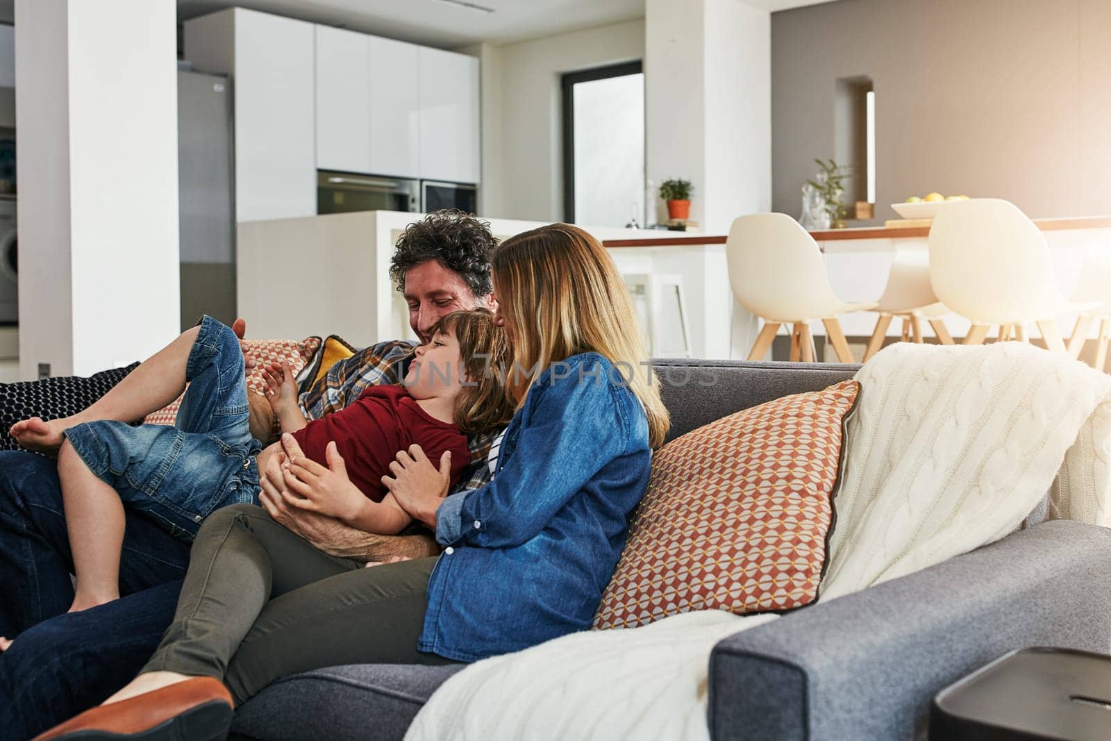 Family is a gift. an affectionate family of three relaxing on the sofa at home. by YuriArcurs