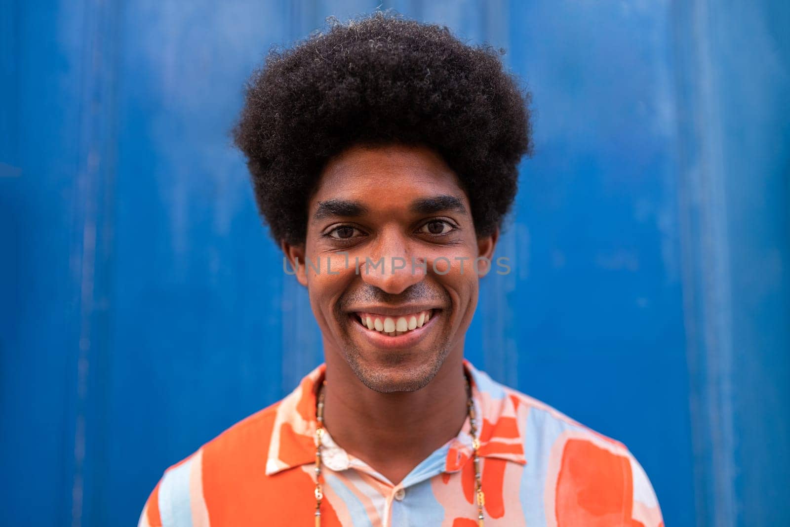 Headshot of smiling young African American man with afro hairstyle looking at camera. Lifestyle concept.