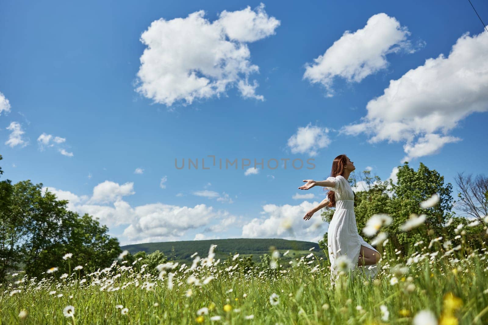 a woman in a light dress runs far across a chamomile field against a blue sky, enjoying harmony with nature by Vichizh