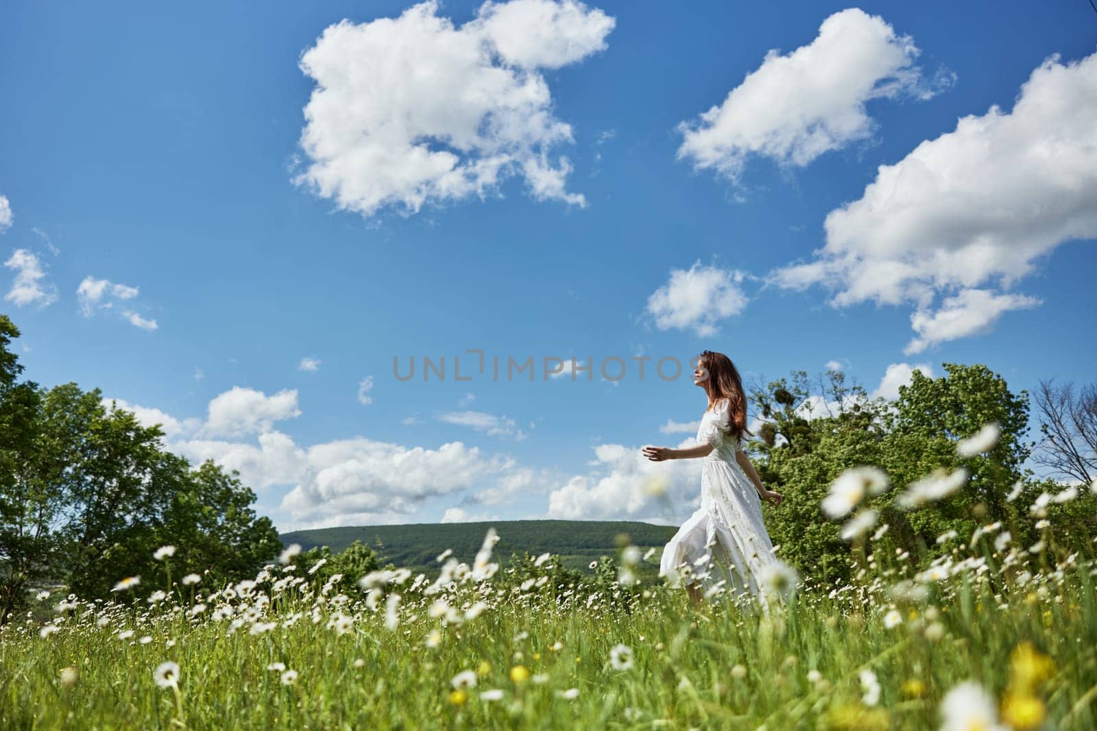 a woman in a light dress runs far across a chamomile field against a blue sky, enjoying harmony with nature. High quality photo