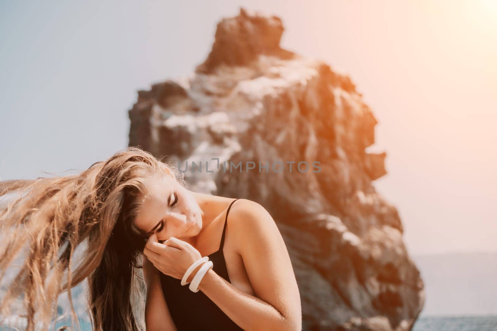 Woman travel sea. Young Happy woman in a long red dress posing on a beach near the sea on background of volcanic rocks, like in Iceland, sharing travel adventure journey