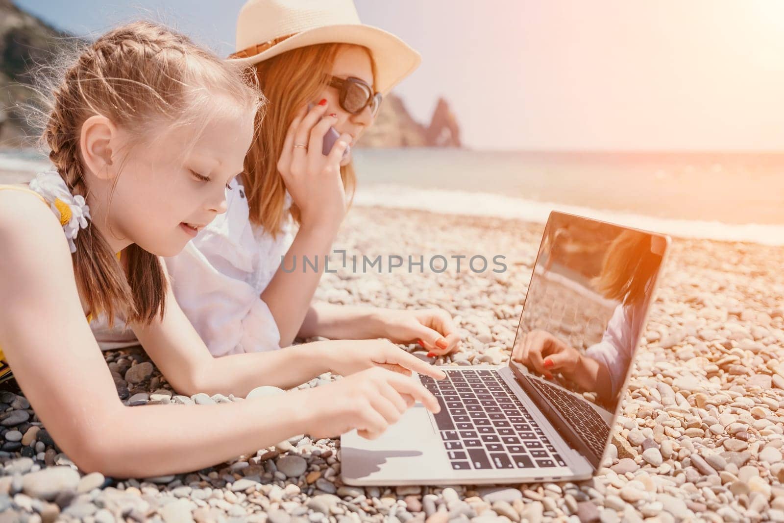 Woman sea laptop. Business woman with daughter, working on laptop by sea. Close up on hands of pretty lady typing on computer outdoors summer day. Freelance, digital nomad, travel and holidays concept by panophotograph