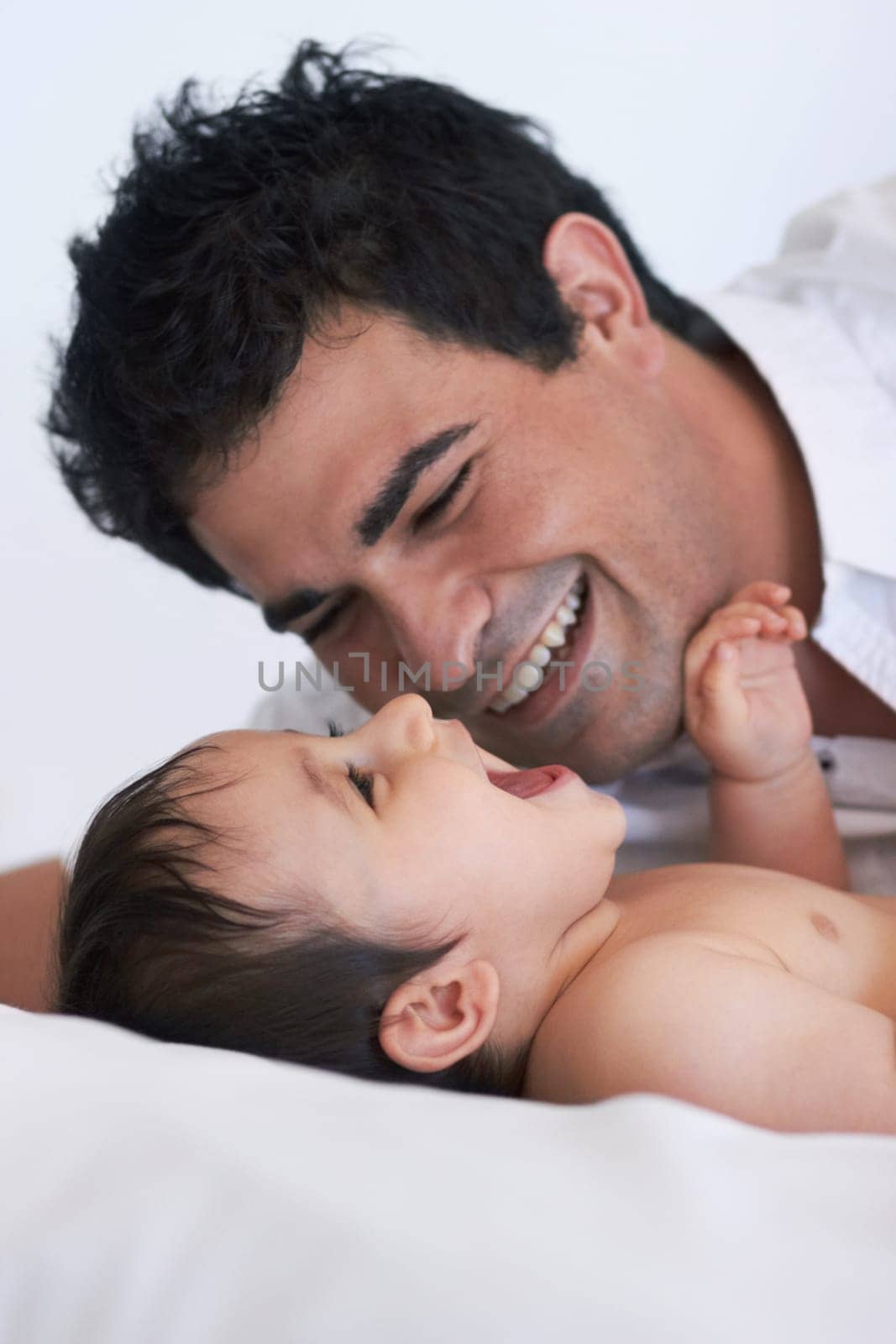 Baby, laugh and dad on a bedroom bed with happiness, bonding and parent care with smile. Father, happy and young child together in a home playing and kid laughing from papa love and youth support.