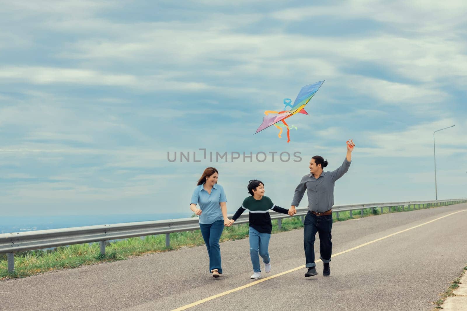Progressive happy family vacation concept with outdoor flying kite on the road by biancoblue