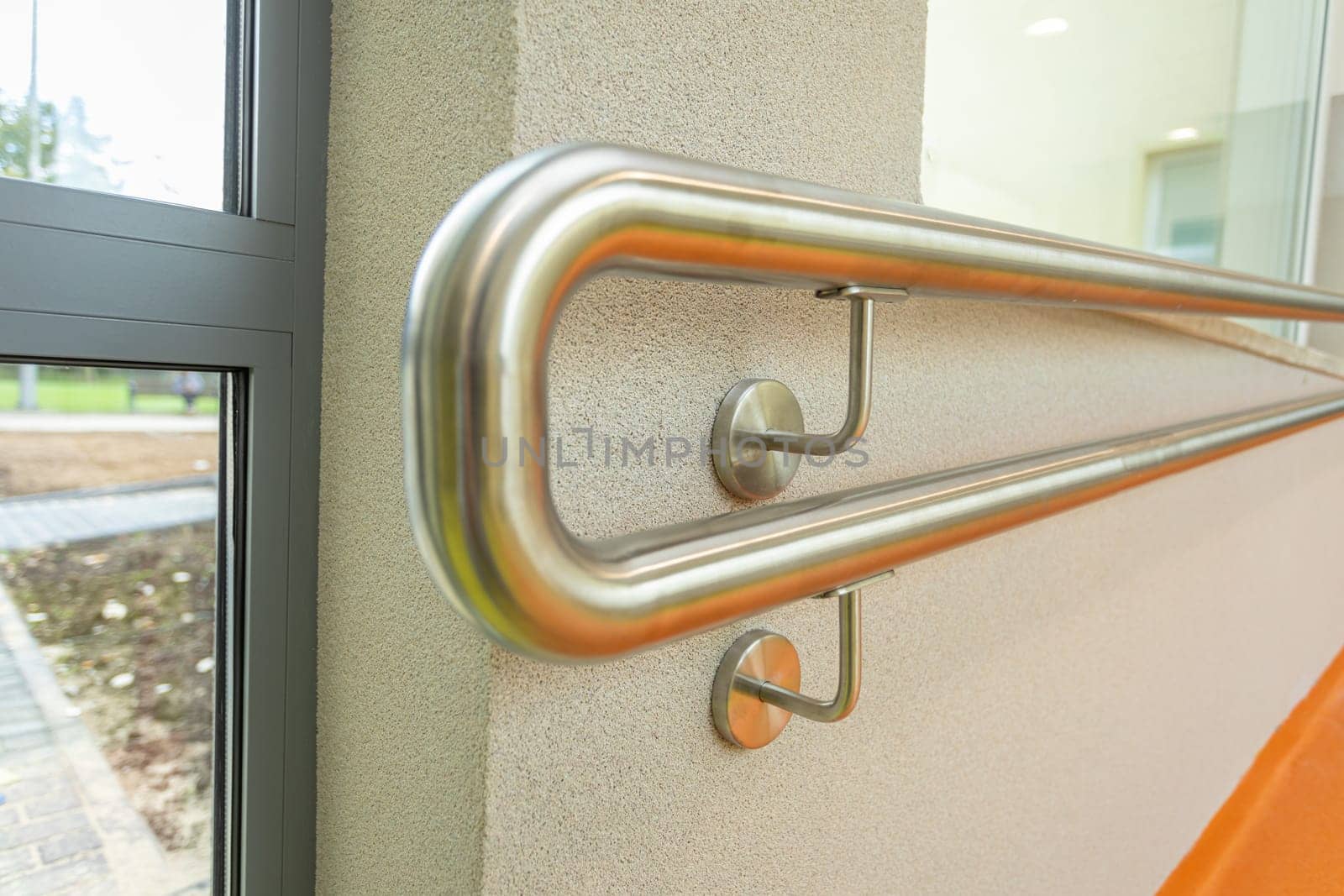 A stainless steel pipe mounted to the wall and serves as a handhold for people walking there.